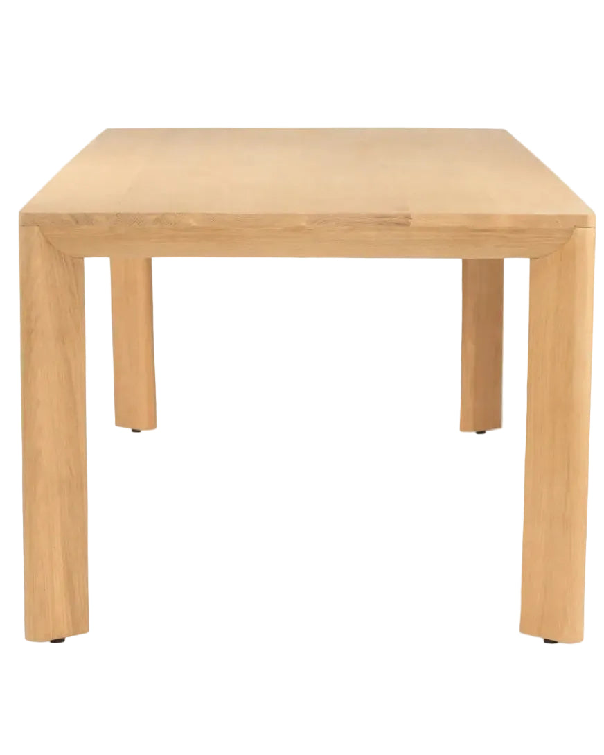 A light natural wood dining table with a square top and four thick block legs, shown from a front-facing perspective on a white background. Aire Dining Table | Rustic Charm Interiors 