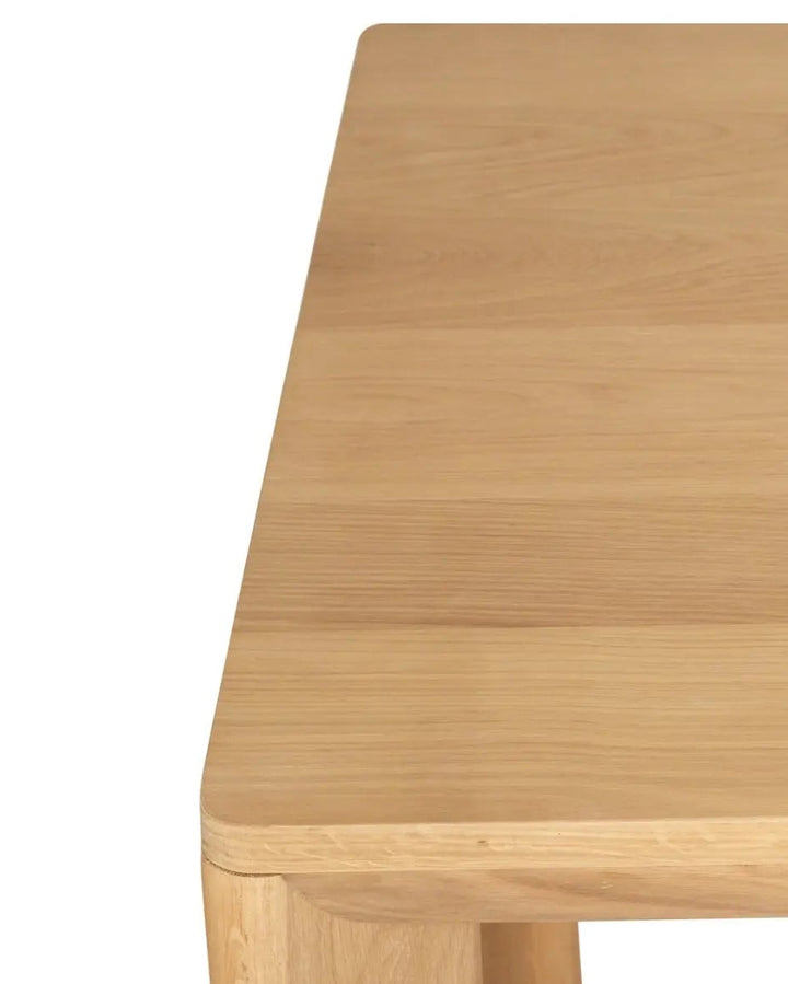 Close-up of a light natural wood tabletop showing the grain and corner detail against a white background.
