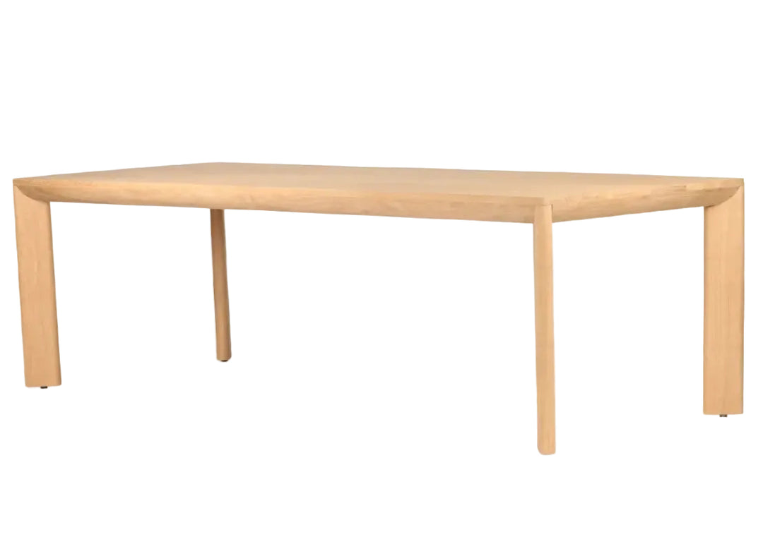 A minimalist rectangular wooden table with a light natural oak finish, featuring a thick top and tapered legs, shown on a solid white background.