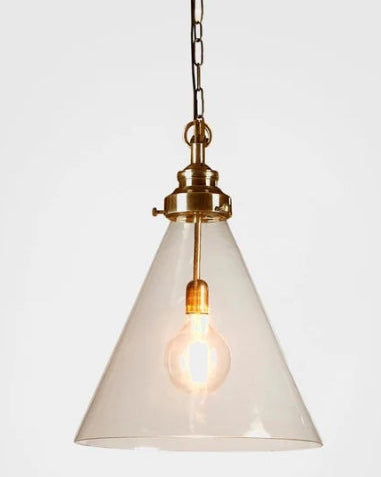 A cone-shaped pendant light with a clear glass shade and a brass-finished metal fixture, suspended by a chain against a plain light gray background.