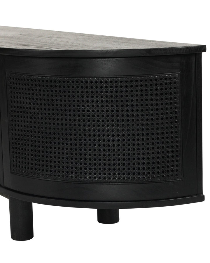 Close-up of a black wooden cabinet with a curved front, woven cane panel doors, and a dark top on a white background.