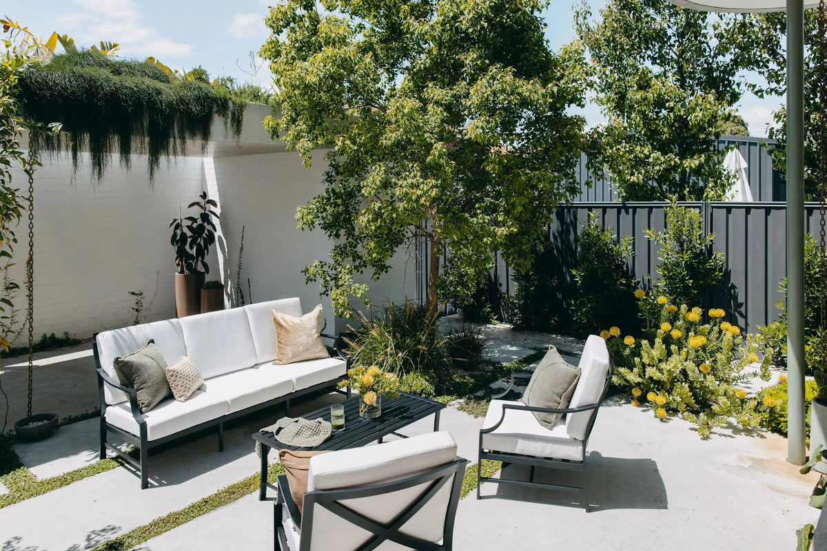 Portofino Lounge Set in Black styled in outdoor space in full sun. 