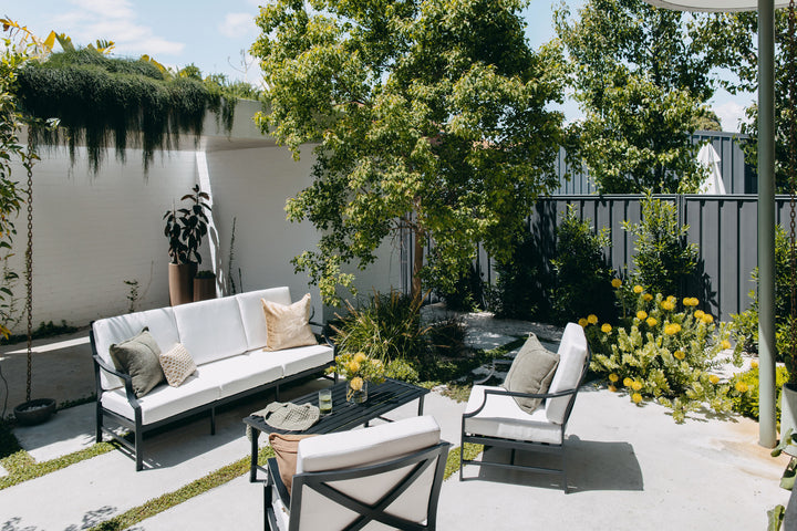 Portofino Lounge Set in Black styled in outdoor space in full sun. 