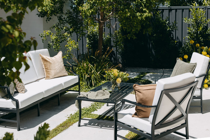 Portofino Outdoor Lounge Set styled in a courtyard garden setting with trees and greenery
