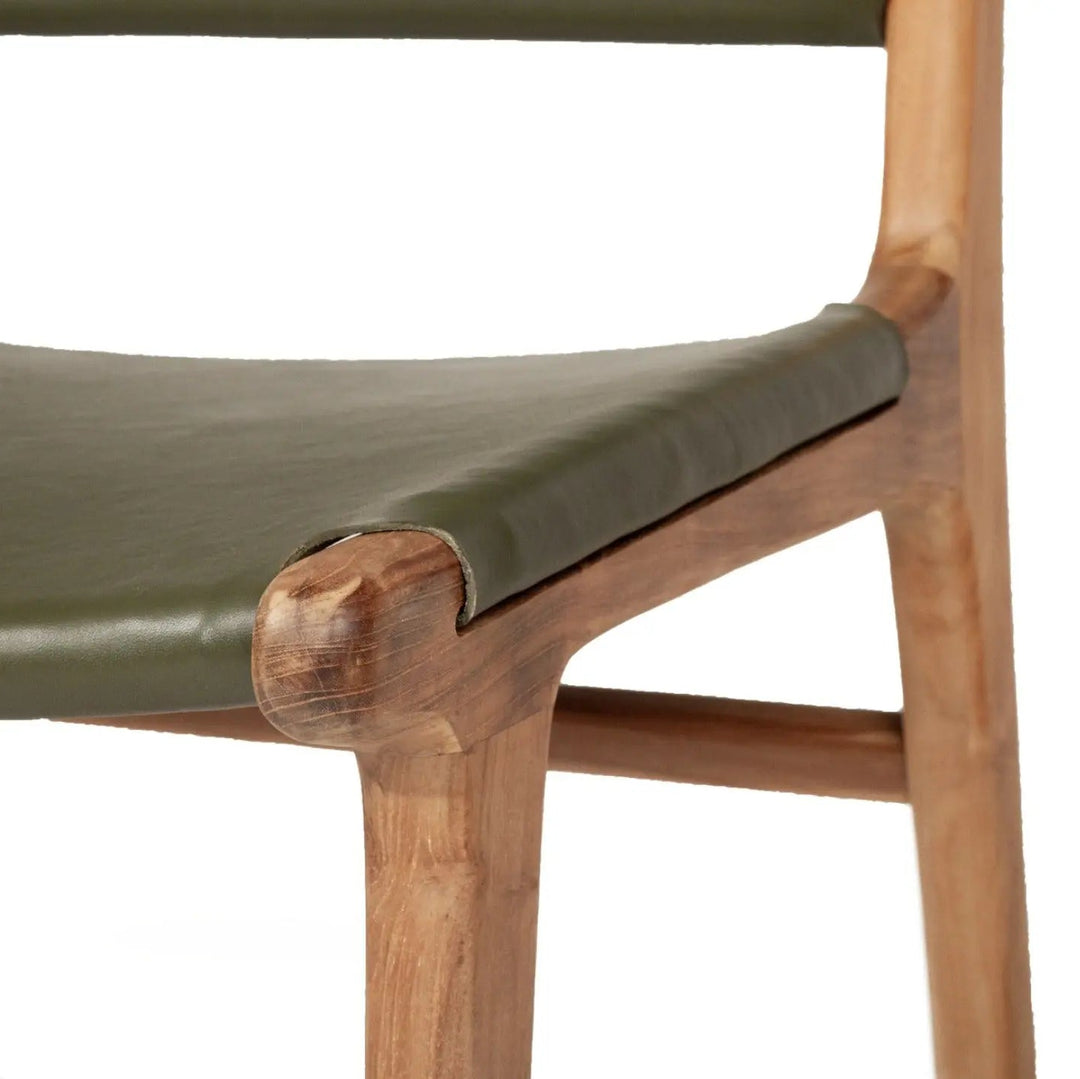 A contemporary Sutton Leather Dining Chair with a teak wooden frame, and olive green leather upholstery.
