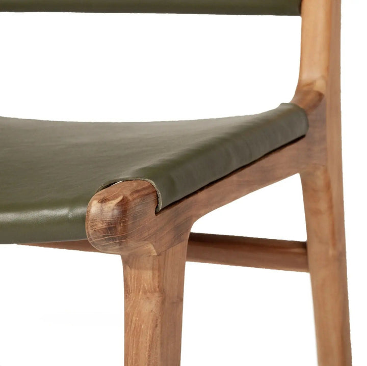 A contemporary Sutton Leather Dining Chair with a teak wooden frame, and olive green leather upholstery.