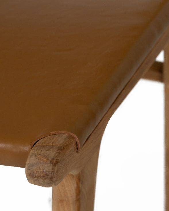 A modern Sutton Leather Dining Chair with a teak wooden frame, and brown leather upholstery.